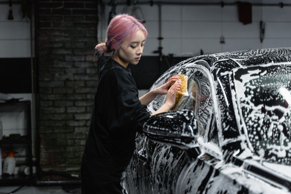 Smiling car wash worker proud of a clean vehicle